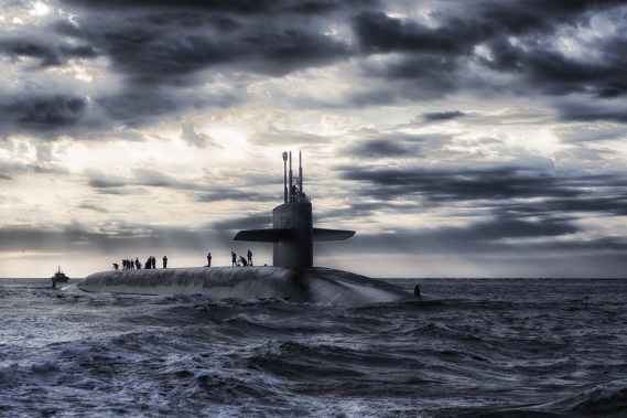 grey submarine in body of water under cloudy sky